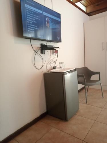 Un televisor de pantalla plana colgado en una pared en PARK FRONT LODGE, en Polokwane