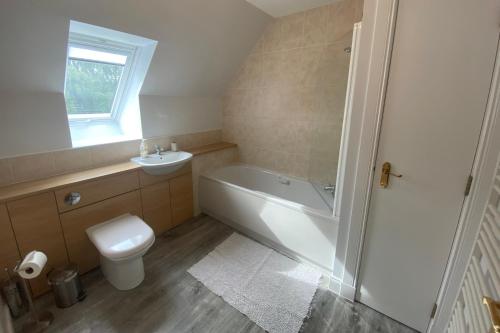 a bathroom with a toilet and a tub and a sink at Carn Avie House in Aviemore