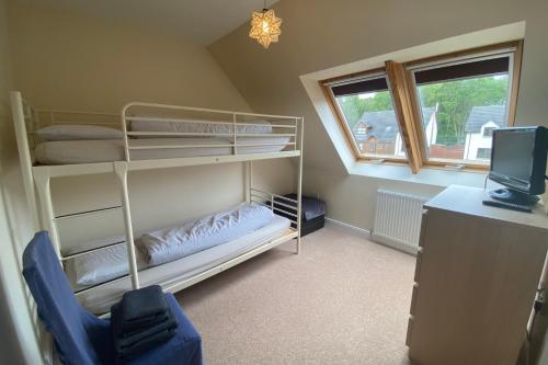 a bedroom with bunk beds and a tv and a window at Carn Avie House in Aviemore