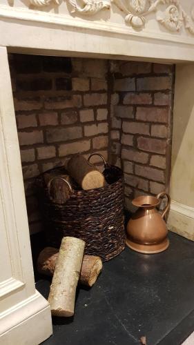 a brick fireplace with two baskets and a tea pot at Riverside Stamford Stays in Stamford