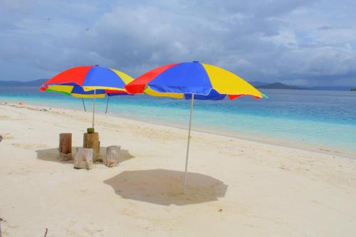 two colorful umbrellas on a beach near the water at Raja Ampat Jousuba Homestay in Minyaifuin