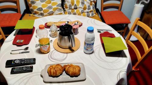 una mesa blanca con comida y bebidas. en Chambre d'hôtes Juline 
