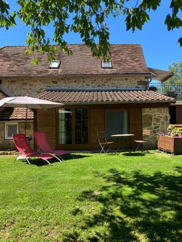 a house with two chairs and a table in the yard at Le Petit Appartement `a Cariad La Rebeuse in Corgnac-sur-lʼIsle