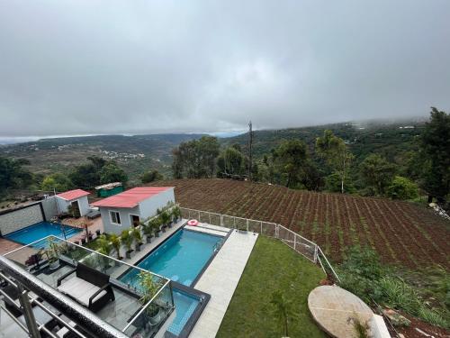 a house with a swimming pool next to a vineyard at Jumbo Heavens 5 Bedroom Scenic Luxury Pool Villa in Mahabaleshwar