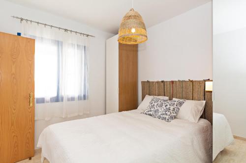 Un dormitorio con una cama blanca y una lámpara de araña. en Villa Pilak, en Playa Blanca