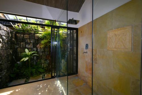 a glass shower in a bathroom with a stone wall at Elegant Villa with pool and privacy Blue Bay in Blue Bay