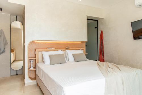 a bedroom with a large white bed and a tv at Esperanto Seafront suites in Nea Kydonia