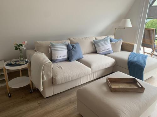 a living room with a white couch with blue pillows at Glückshaus in Brodersby