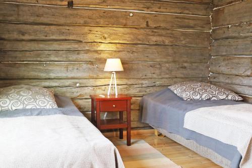a bedroom with two beds and a lamp on a table at Kainuun Luontoretket in Hossa