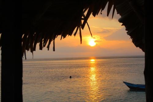 a sunset over the ocean with a boat in the water at Raja Ampat Jousuba Homestay in Minyaifuin