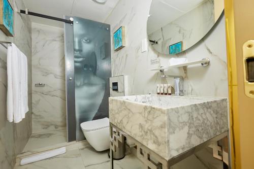 a bathroom with a toilet, sink, and bathtub at Number One Oxford Street Hotel & Suites, a member of Radisson Individuals in Accra