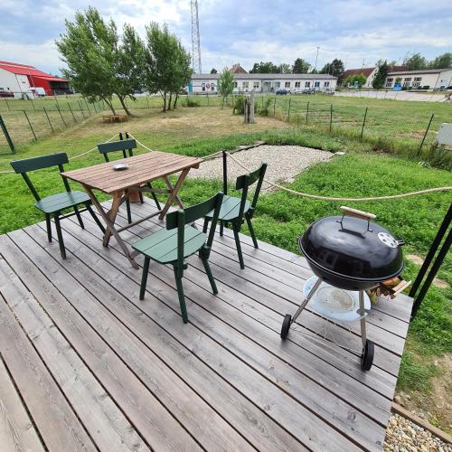 a grill on a wooden deck with a picnic table and chairs at Tiny House in Neusiedl an der Zaya