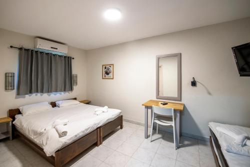 a bedroom with a bed and a table and a mirror at כפר הנופש קיבוץ גדות Kibbutz Gadot Galilean Resort in Gadot