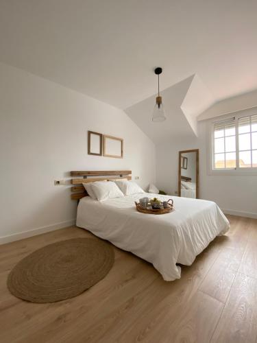 una camera bianca con un grande letto e un tavolo sopra di "A Marosa", bonito chalet dúplex a Cangas de Morrazo