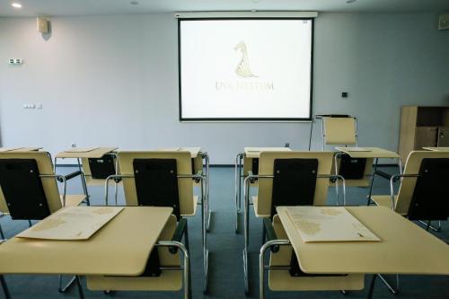 an empty classroom with tables and chairs and a screen at Uva Nestum Wine & SPA in Gotse Delchev