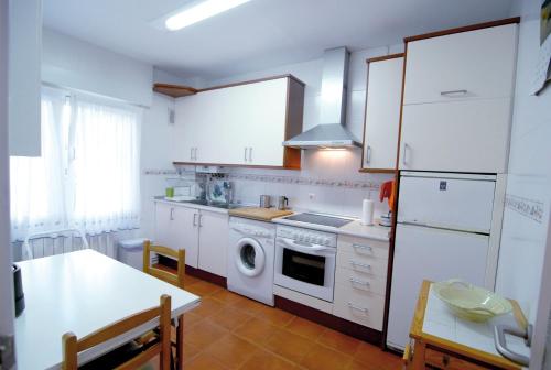 a kitchen with white cabinets and a washer and dryer at Confortable y amplio piso en Mundaka in Mundaka