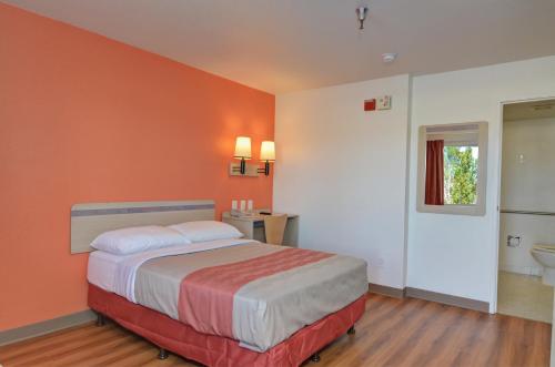 a bedroom with a bed with an orange wall at Motel 6-Twentynine Palms, CA in Twentynine Palms