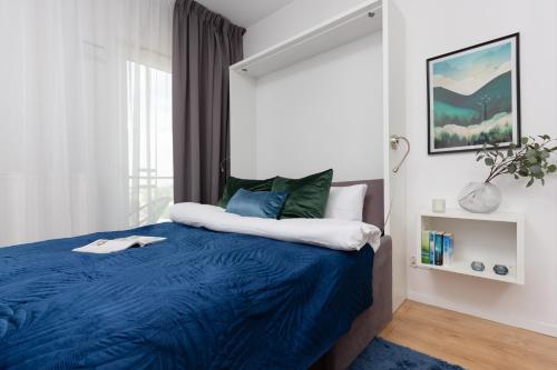 ein Schlafzimmer mit einem blauen Bett und einem Fenster in der Unterkunft Apartments Varsovia Kasprzaka by Renters in Warschau
