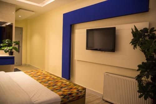 a room with a tv on a wall with a bed at Metropole Hotel in Murree