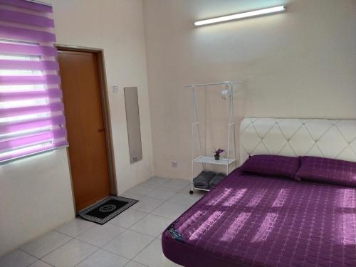 a purple bed in a room with a window at WAFID HOMESTAY SERI ISKANDAR in Seri Iskandar