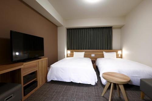 a hotel room with two beds and a flat screen tv at Dormy Inn Express Fujisan Gotemba in Gotemba