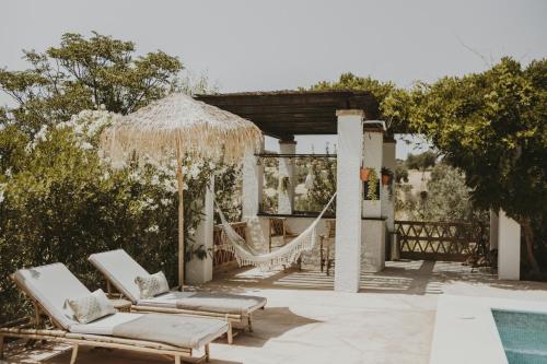 a pair of lounge chairs and an umbrella next to a pool at Hacienda el Tarajal in Priego de Córdoba