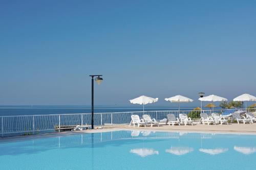uma piscina com cadeiras e guarda-sóis junto ao oceano em FKK Solaris Camping Resort by Valamar em Porec