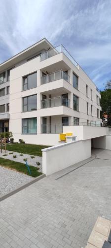 a white building with a yellow bench in front of it at Mazurski relax plus Taras Garaż podziemny in Węgorzewo