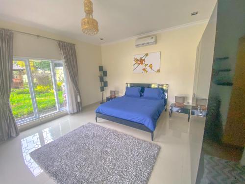 a bedroom with a blue bed and a large window at Villa Andalus 1&2 in Puncak