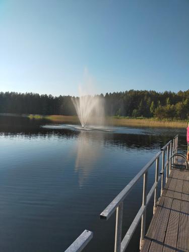 una mujer sentada en un muelle mirando un lago en 2-ju kambariu butas, en Ignalina