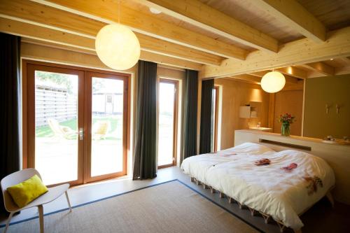 een slaapkamer met een bed en een groot raam bij Bed & Coffee Skilleplaatsje in Den Burg