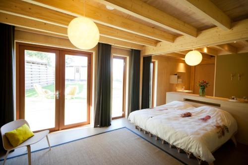 a bedroom with a bed and a large window at Bed & Coffee Skilleplaatsje in Den Burg