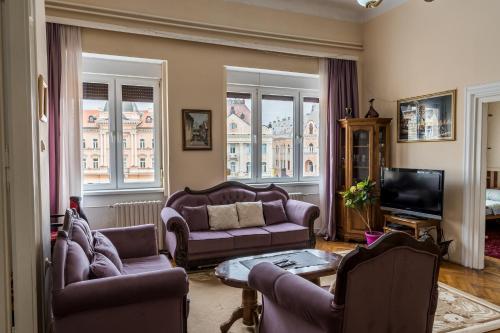 a living room with purple couches and a tv at Apartment Panorama Central in Novi Sad