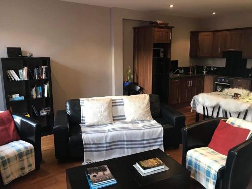 a living room with a couch and chairs and a kitchen at Centre of Dingle Town - Luxury Holiday Apartment in Dingle