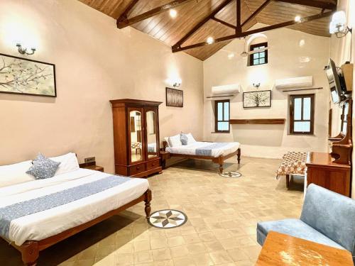 een slaapkamer met 2 bedden en een bank en een stoel bij Hotel Mount View Heritage in Panchgani