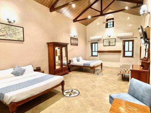 a bedroom with two beds and a couch and a chair at Hotel Mount View Heritage in Panchgani