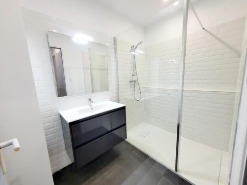 a white bathroom with a sink and a shower at Le Bastide Cosy in Carcassonne