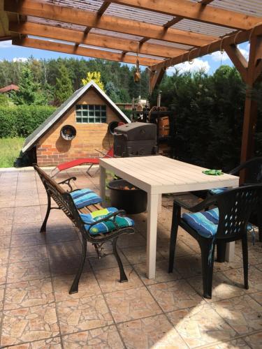a picnic table and two chairs under a pergola at Bungalow nebst Wohnwagen für 4 bis 5 Personen in Nähe von See- und Tesla 