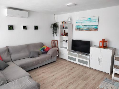 sala de estar con sofá y TV en Apartamento Ciudamar, en Puerto Sagunto