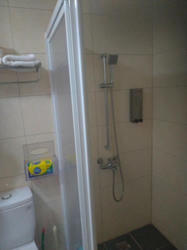 ducha con puerta de cristal junto a un aseo en mei hao min su en Nangan