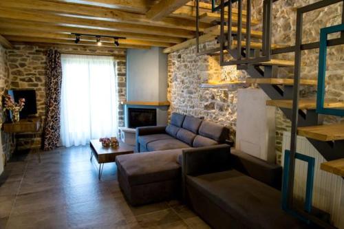 a living room with a couch and a stone wall at Guesthouse Iris in Tsagarada