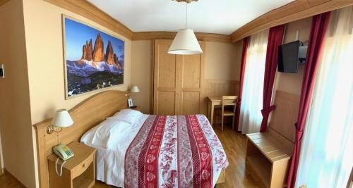 a bedroom with a bed and a picture on the wall at Albergo Garnì Ajarnola in Auronzo di Cadore