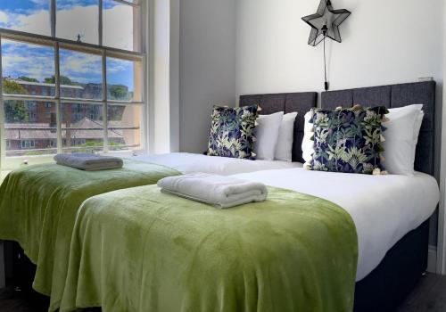1 dormitorio con 2 camas con sábanas verdes y ventana en Valley Garden View 4 By My Getaways en Brighton & Hove