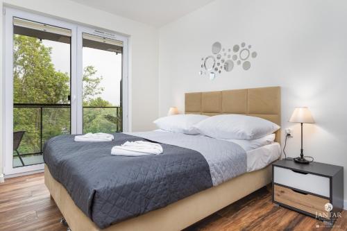 biała sypialnia z dużym łóżkiem i oknami w obiekcie Jantar Apartamenty- Wyspa Solna w Kołobrzegu
