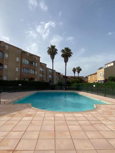 - une piscine dans une cour bordée de palmiers dans l'établissement Les locations Cinaureva « La Baie des Îles », à La Londe-les-Maures