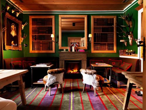a green room with two chairs and a fireplace at House of Hütter - Wachtelhof & SPA in Maria Alm am Steinernen Meer