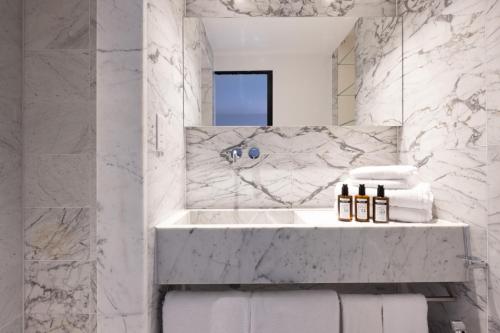 a white bathroom with a sink and a mirror at La Suite West - Hyde Park in London