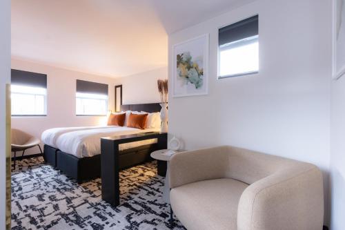 a bedroom with a bed and a chair and a couch at La Suite West - Hyde Park in London