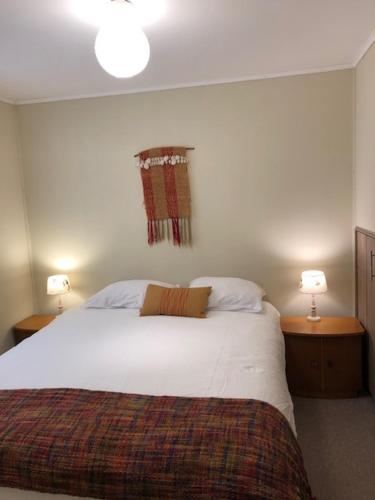 a bedroom with a large white bed with two lamps at Casa Linden in Valdivia