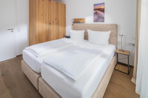 een groot wit bed in een kleine kamer bij Friesenhuus Friesenhuus Norderney, Whg 02 in Norderney